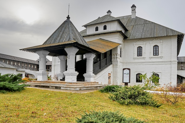 A two-story white monastery building with a wooden roof. Kazan