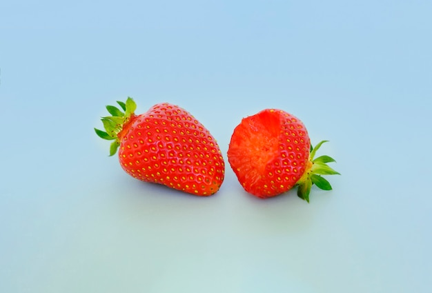Two strawberries with strawberry leaves on a gray background