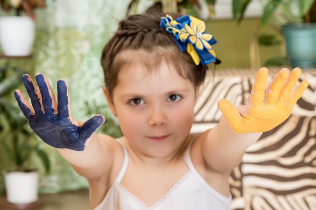 Две вытянутые вперед руки ребенка покрасили одну в синий цвет, другую в желтый