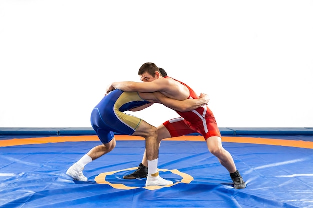 Foto due uomini forti in collant da wrestling blu e rosso stanno lottando su uno sfondo bianco.