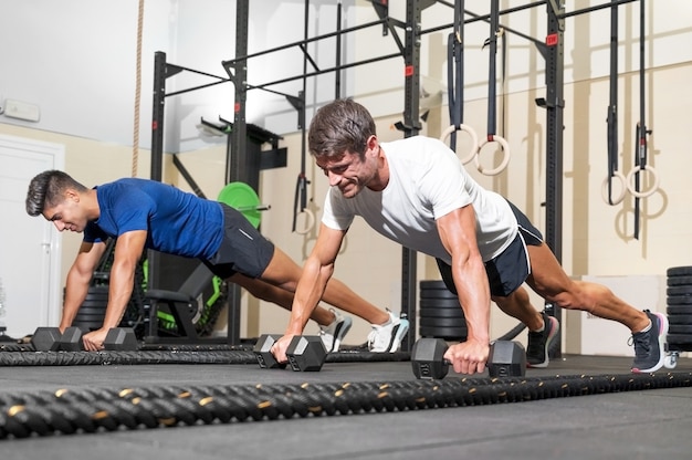 Two strong men doing pushups in gym