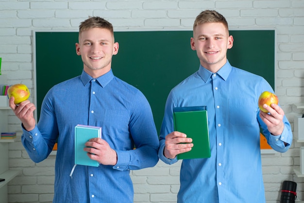 Two student holding books and smiling at camera Learning and education concept Group of high school students in classroom