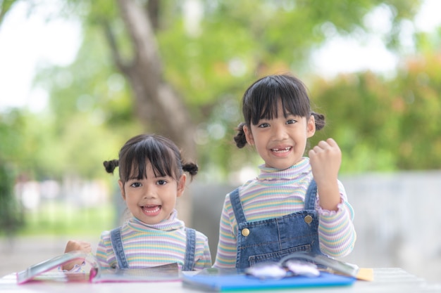 写真 テーブルの上の本を読んでいる2人の学生の小さなアジアの女の子