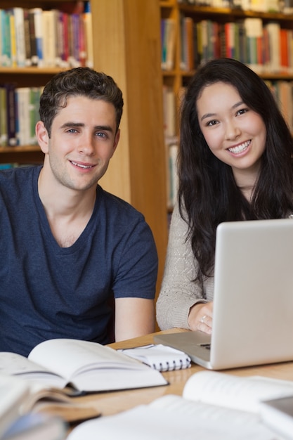 Photo two students learning with a laptop in a library