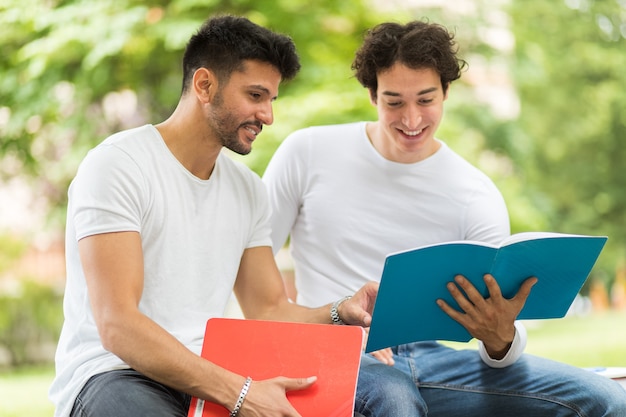 Two students studying together sitting on a bench outdoor