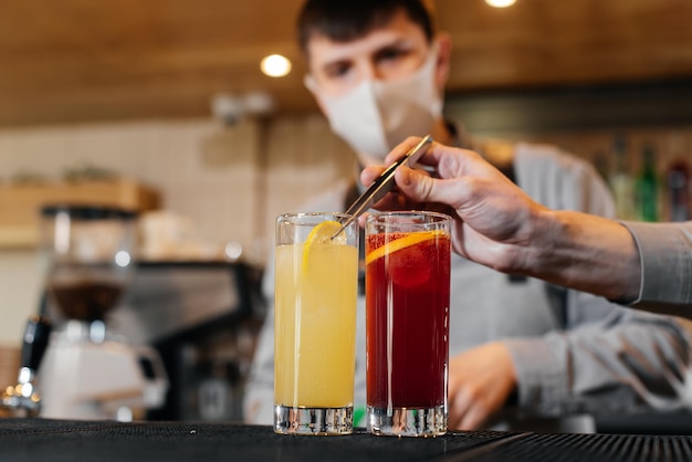 Two stylish bartenders in masks and uniforms are preparing cocktails at a party during a pandemic The work of restaurants and cafes during the pandemic