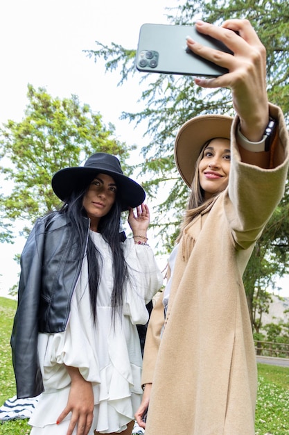 Photo two stylish friends taking a selfie at the park
