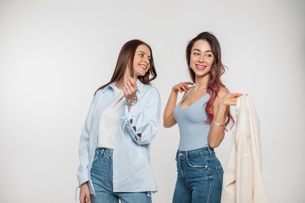 Two stylish happy positive young girls with a smile in fashion denim casual clothes poses and having fun on a white background