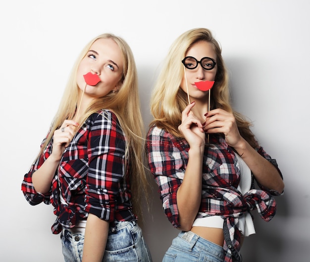 Two stylish sexy hipster girls best friends ready for party, over gray background