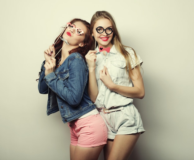 Two stylish sexy hipster girls best friends ready for party, over gray surface