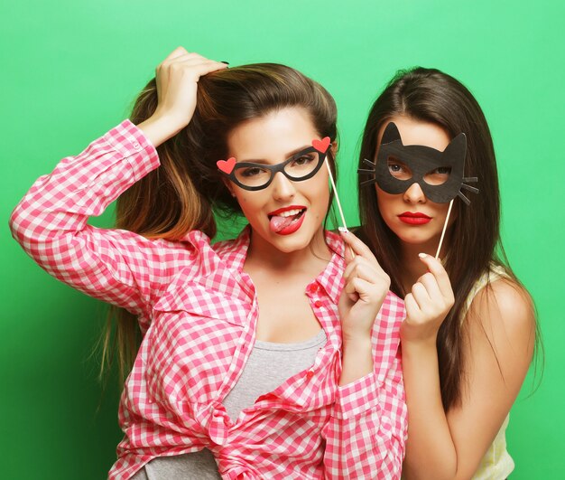 Two stylish sexy hipster girls best friends ready for party, over green background