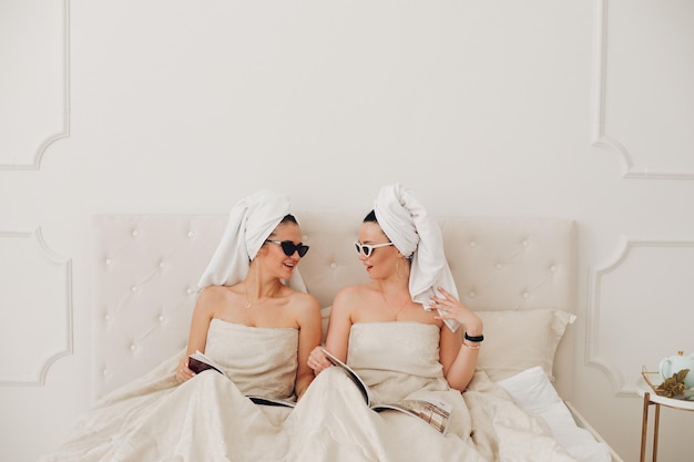 Two stylish women in jewelry resting in bedroom