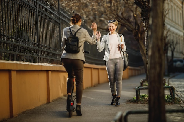 A two successful businesswomen greeting while going to work through the city.