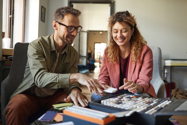 Two successful designers sitting at the table with colored patterns and planning the work at office