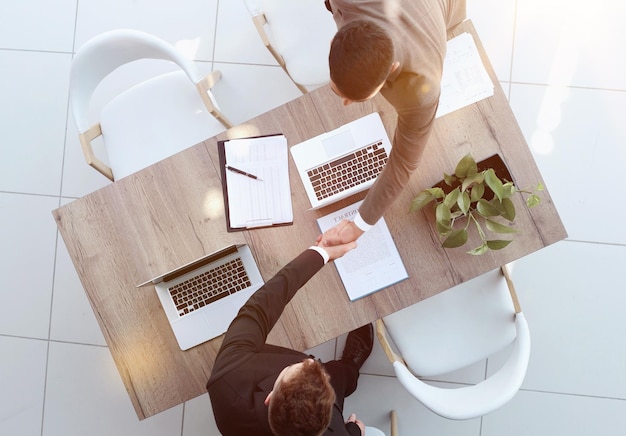 Two successful smiling businessmen are working on a laptop view from above