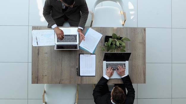 Two successful smiling businessmen are working on a laptop view from above