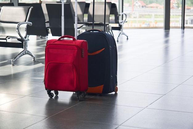 Two suitcases are on the floor in airport waiting room