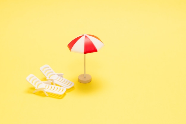 Photo two sun loungers and a red umbrella on a yellow background. copy space.