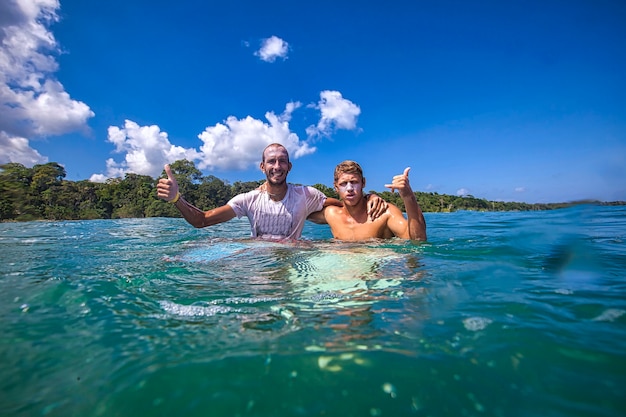 Photo two surfers in an ocean, bali island.