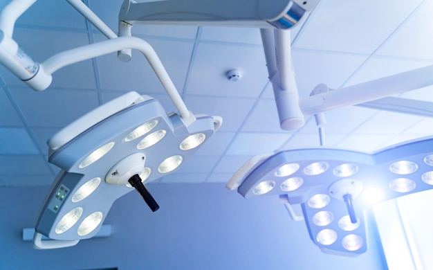 Photo two surgical lamps in operation room. blue cast light in clinic. modern equipment in surgery room. operating theatre. closeup.