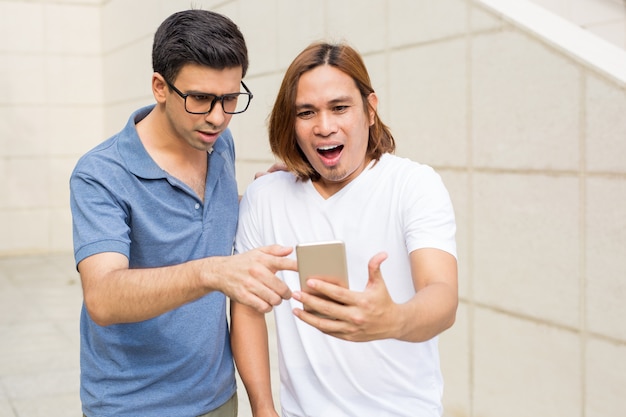 Two Surprised Men Using Smartphone Outdoors