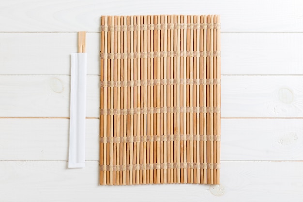 Фото Две палочки для суши с пустой бамбуковой циновкой или деревянной тарелкой на дереве