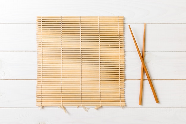 Two sushi chopsticks with empty bamboo mat on wood