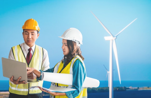 Photo two sustainable energy engineer male and female is discussing on document plant with wind turbine.