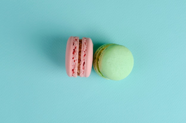 Two sweet french desserts of pastel green and pink colors macaroons on pastel blue