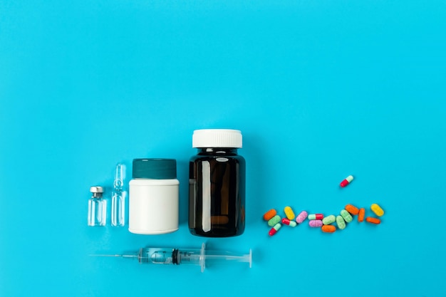 Two syringe bottles for medicines of white and brown color with typed medicine and scattered tablets on a blue .Health . The  of medicine. 