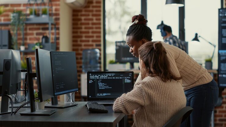 Photo two system engineers analyzing source code on laptop looking for errors on screen while sitting at desk. team of app developers working on group project for ai online cloud computing project.