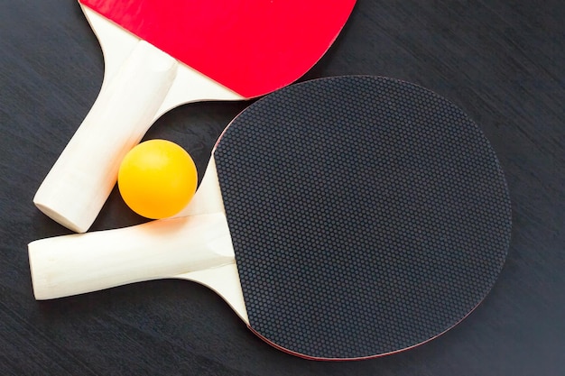 Two table tennis or ping pong rackets and ball on a black background