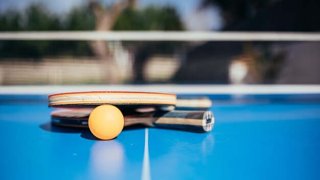 Two table tennis rackets next to the ball and the net in the background