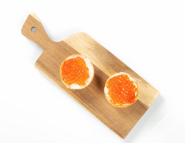 Two tartlets filled with red salmon caviar on a wooden kitchen board top view