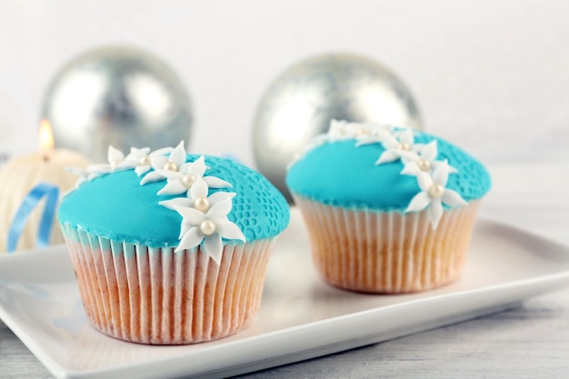 Two tasty blue cupcakes with decorations on light background