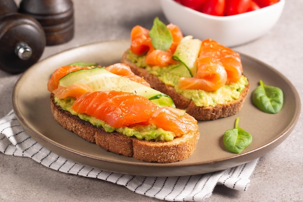 Foto due gustosi panini al salmone aperti con avocado e cetriolo. mattina sana colazione. vista dall'alto.