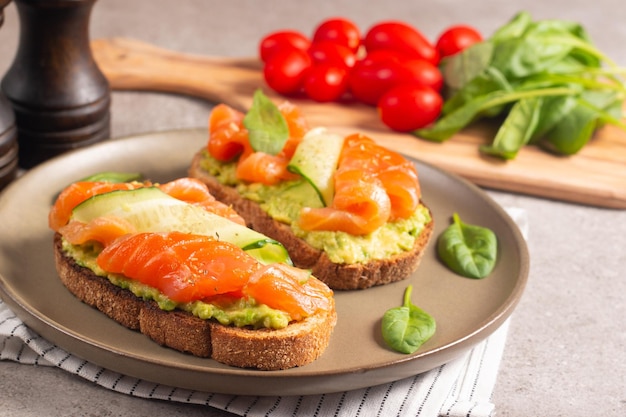 Two tasty open salmon sandwiches with avocado and cucumber. Morning healthy breakfast. Top view.