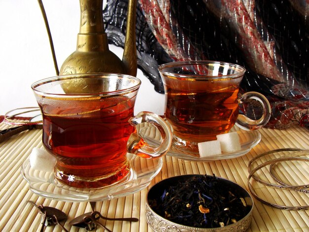 two tea cups with tea in them and one of them has a gold leaf