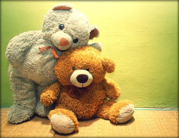 Photo two teddy bears against yellow wall