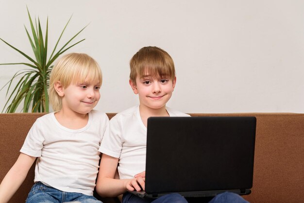 Фото Два подростка сидят на диване с ноутбуком в руке и улыбаются