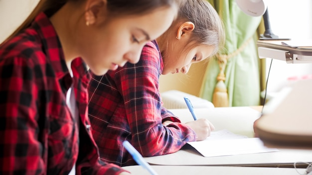 Фото Две девочки-подростки делают домашнее задание в школе на самоизоляции.