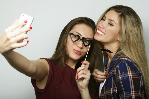 Two teenage girls friends in hipster outfit make selfie on a phone.