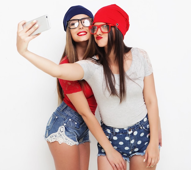 Two teenage girls friends in hipster outfit make selfie on a phone.