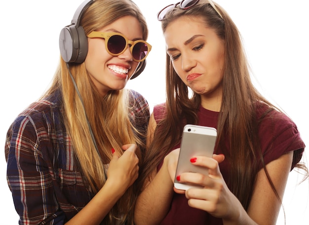 Due amiche adolescenti in abito hipster fanno selfie su un telefono.