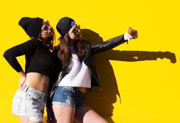 Photo two teenage girls friends in hipster outfit outdoors make selfie on a phone
