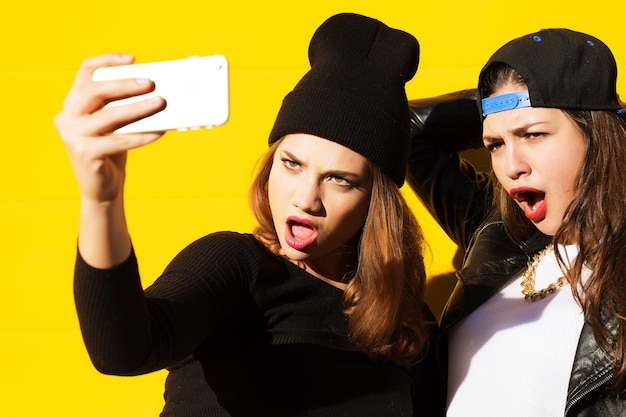 Photo two teenage girls friends in hipster outfit outdoors make selfie on a phone