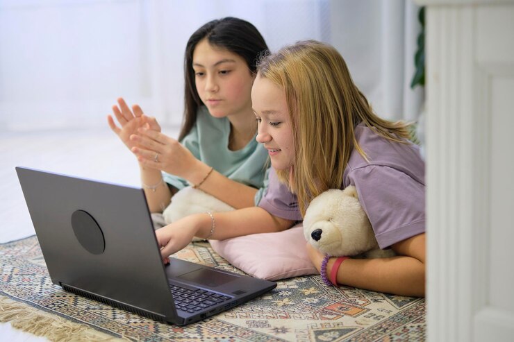 Photo two teenage girls lie on the bedroom floor and watch a movie on a laptop friendship concept