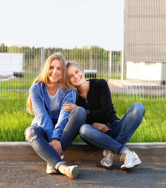 Two teenage girls sitting together outdoors