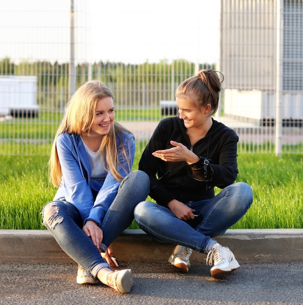 Two teenage girls sitting together outdoors