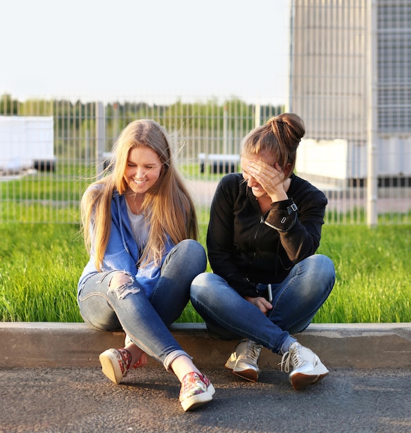 Two teenage girls sitting together outdoors